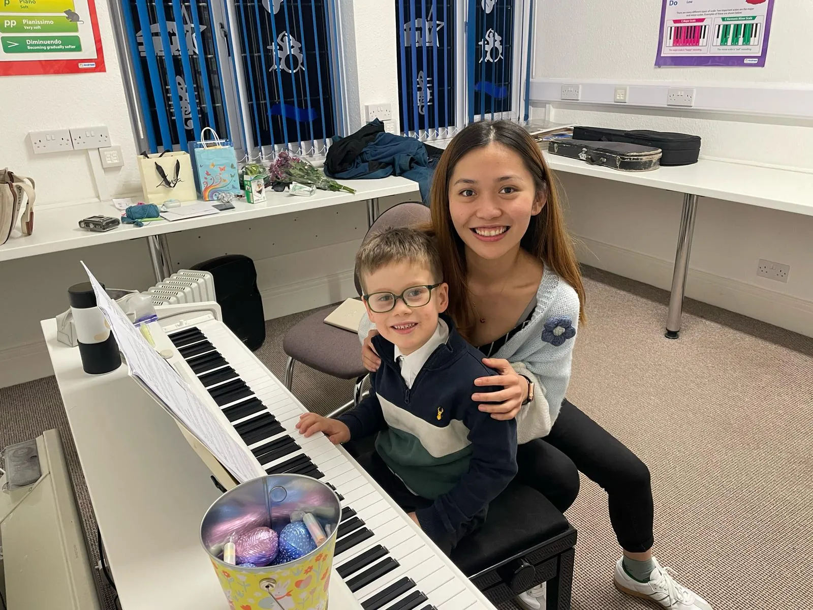 Agnes beside a young pupil seated at the piano in a teaching room